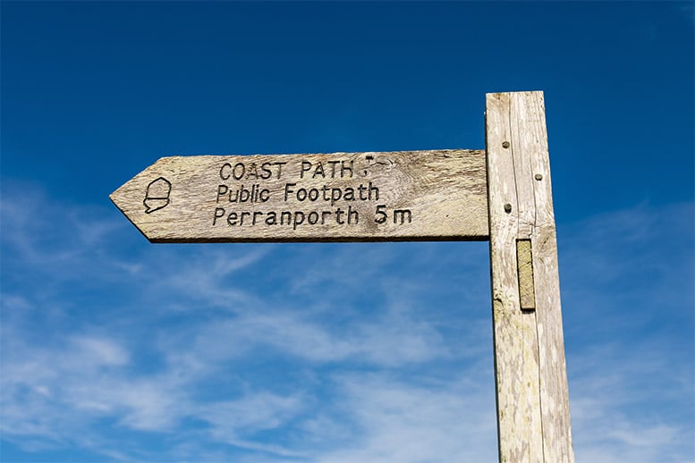 A wooden sign directing people to the coast path at Perranporth